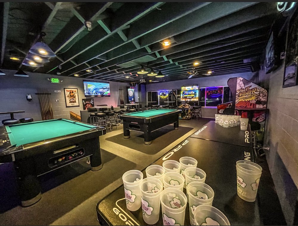 The games floor at The Blue Moon Lounge - two pool tables, a Pong PRO beer-pong table set up with cups in the foreground, and a dartboard on the back wall